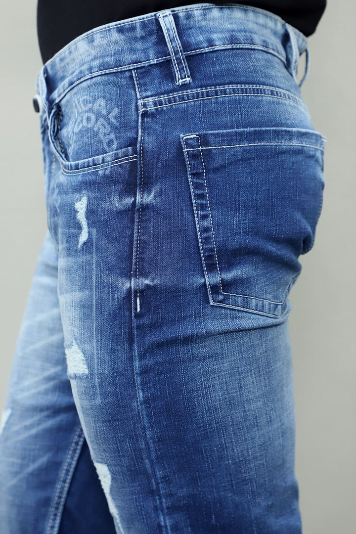 Close up of distressed patch detail on GEX men's blue slim fit stretch jeans E13