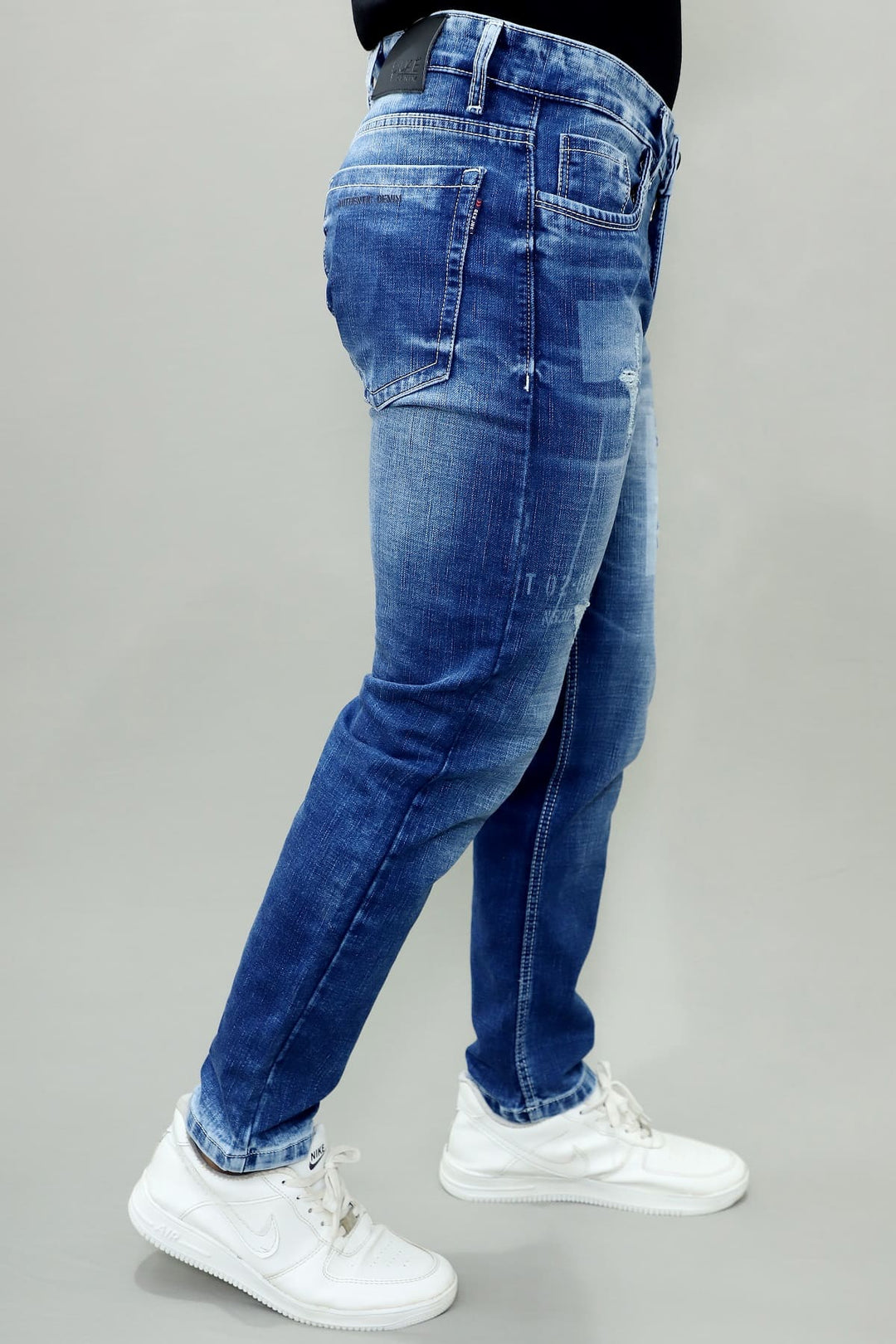 Side view of GEX men's blue distressed slim fit stretch jeans with stylish patch denim E13