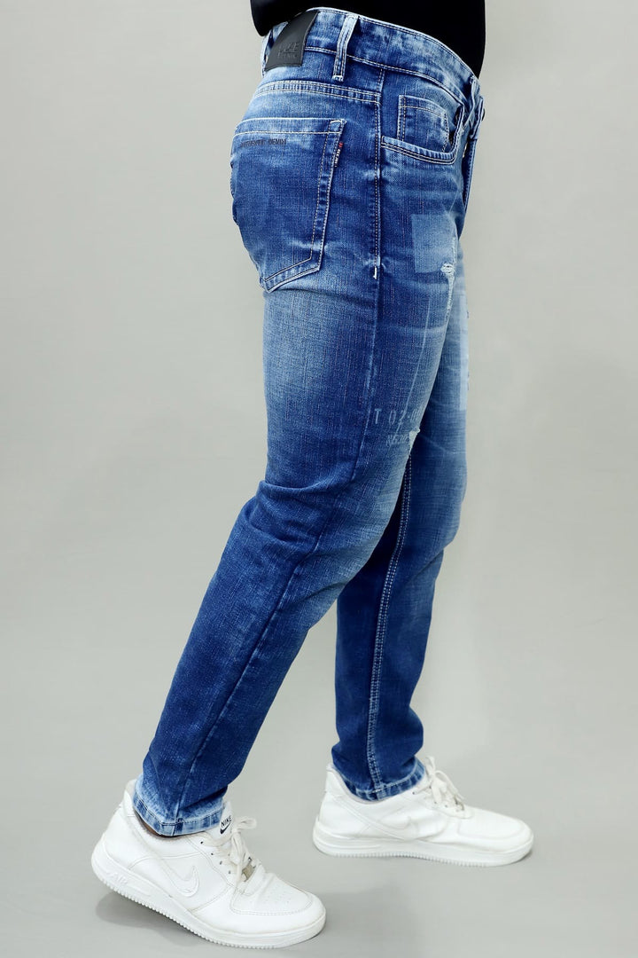 Side view of GEX men's blue distressed slim fit stretch jeans with stylish patch denim E13
